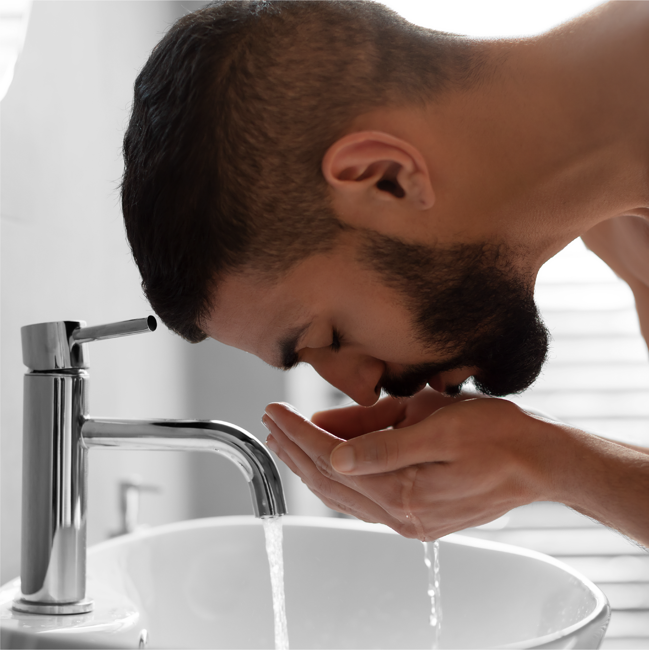 Man washing face and beard over sink
